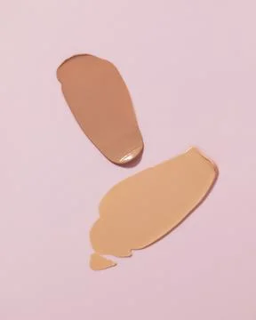 Makeup foundation, beige concealer swatch smudge smear on pink background. Stock Photos