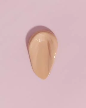 Makeup foundation, beige concealer swatch smudge smear on pink background. Stock Photos