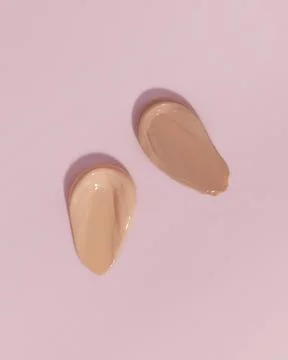Makeup foundation, beige concealer swatch smudge smear on pink background. Stock Photos