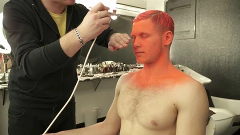 Makeup master covers model's hair and face with the orange color Stock Footage 73537445