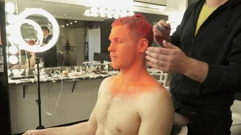 Makeup master covers model's hair with orange color in the studio Stock Footage 73537501