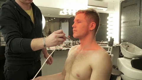Makeup master sprays orange color to the model's face Stock Footage 73519052