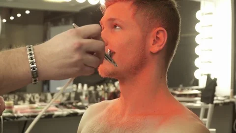Makeup master sprays orange color to the model's face closeup Stock Footage 73519136