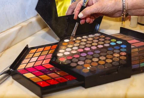 Makeup palette with hand picking eyeshadow using a brush Stock Photos