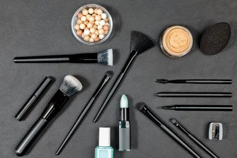 Makeup products and tools with different brushes on black background Stock Photos