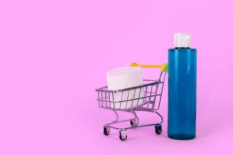 Makeup remover in plastic blue bottle on a pink background, cotton cosmetic.. Stock Photos