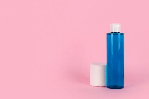 Makeup remover in plastic blue bottle on a pink background, cotton cosmetic.. Stock Photos