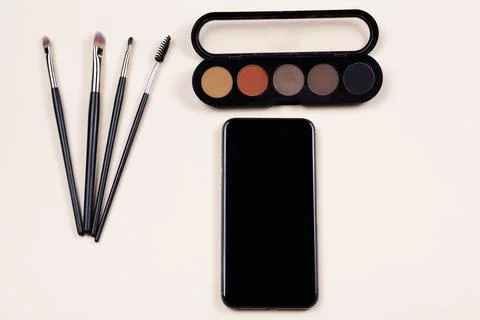 Makeup set and decorative cosmetics near empty black screen mobile phone over 写真素材
