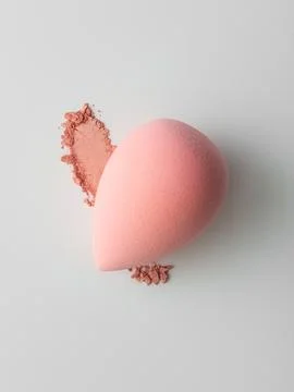 Makeup sponge with smear of blush powder on a light background. Colorful beau Stock Photos
