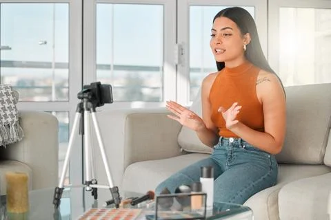 Makeup, streaming and tutorial with woman influencer on sofa in living room of Fotos Stock