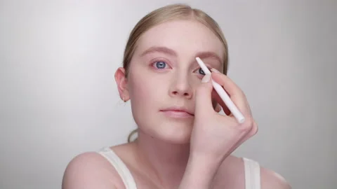 Makeup tutorial: attractive blonde model fills in eyebrows with eyebrow pencil 스톡 동영상 193684844