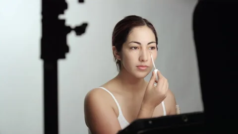 Makeup tutorial: Attractive brunette applies liquid foundation under eyes Stock Footage 193845366