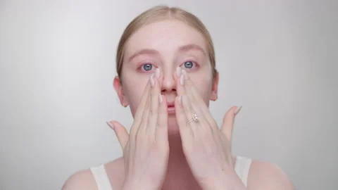 Makeup Tutorial: Blonde model gently applies primer to face with fingers Stock Footage 193670675