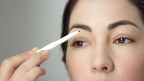 Makeup tutorial: extreme closeup of eyebrow pencil being used by brunette model Stock-Footage 193876276