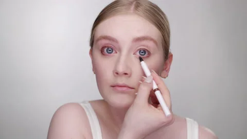 Makeup Tutorial: Lovely blonde model applies eyeliner with eyeliner pencil Видео 193692831