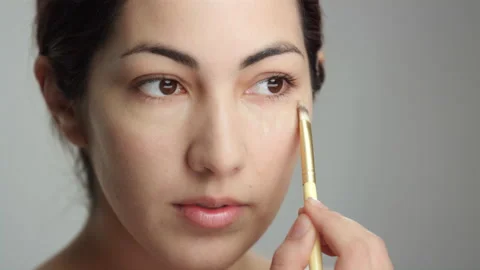 Makeup tutorial: Lovely brunette model works in liquid foundation using brush Stock Footage 193847891
