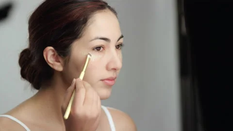 Makeup tutorial: Side view of brunette model brushing in liquid foundation 스톡 동영상 193849026