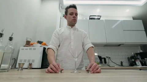 Making an alcoholic cocktail. The bartender stands behind the counter at home an Stock Footage 131536013