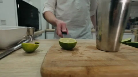 Making alcoholic cocktail. The bartender throws up sliced lime on knifes blade Stock Footage 131546229