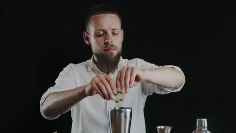 Making alcoholic cocktail. The bartender throws up sliced lime on knifes blade Stock Footage 132764704