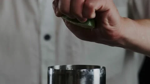 Making alcoholic cocktail. The bartender throws up sliced lime on knifes blade Stock Footage 132765241