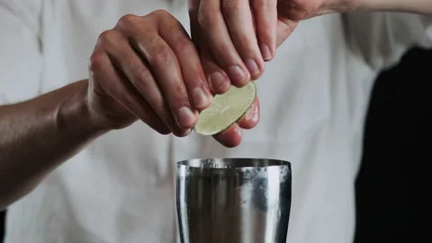 Making alcoholic cocktail. The bartender throws up sliced lime on knifes blade Stock Footage 132765480