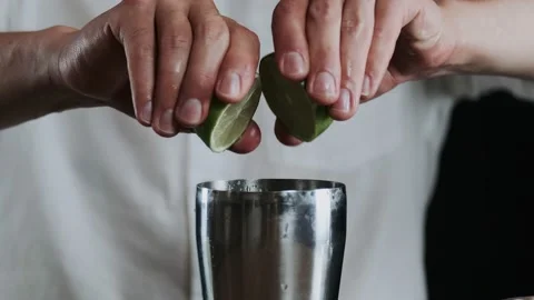 Making alcoholic cocktail. The bartender throws up sliced lime on knifes blade Stock Footage 132765853