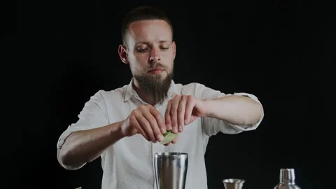 Making alcoholic cocktail. The bartender throws up sliced lime on knifes blade Stock Footage 133984660