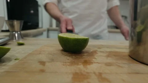 Making alcoholic cocktail. The bartender throws up sliced lime on knifes blade Stock Footage 134034512
