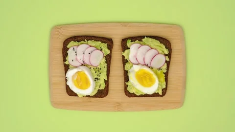 Making and eating rye bread sandwiches with avocado, egg, radish, greenery and Stock Footage 267258393