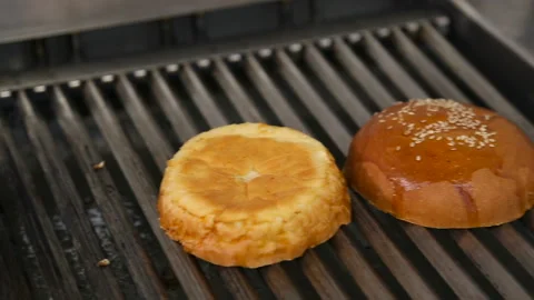 Making and grilling hamburger buns with sesame on coal grill. Preparing roasted Stock Footage 98991310