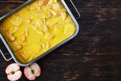 Making an apple pie. Raw dough in a baking dish, apple and sugar on the woo.. Stock Photos