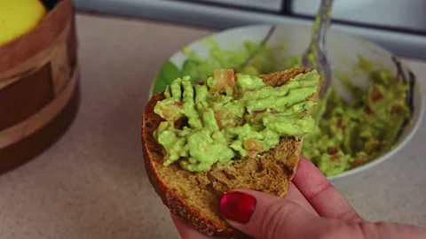 Making avocado toast. Man spread avocado on toasted sandwich bread Stock Footage 171812097