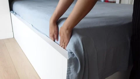 Making a bed with a blue sheet and white base Stock Footage 322871348