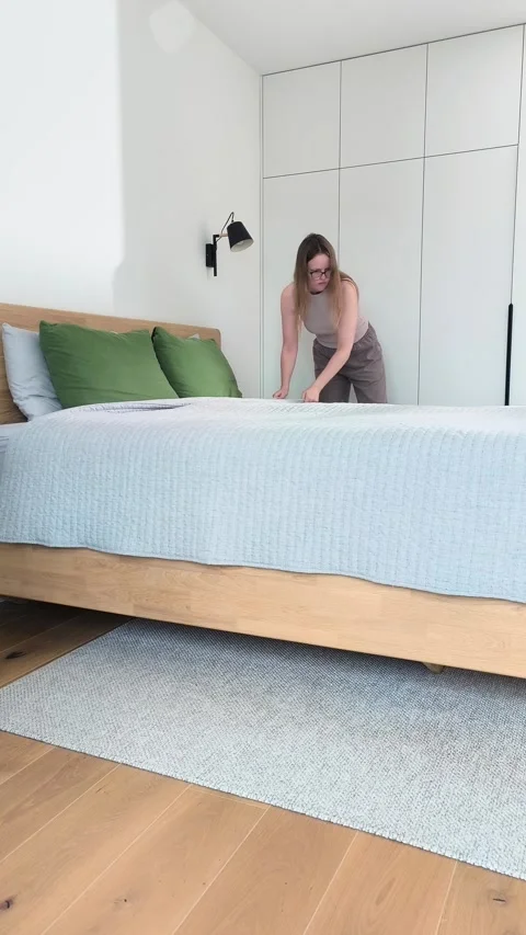 Making bed inside a contemporary bedroom during daily household chores. You.. Stock Footage 346161364