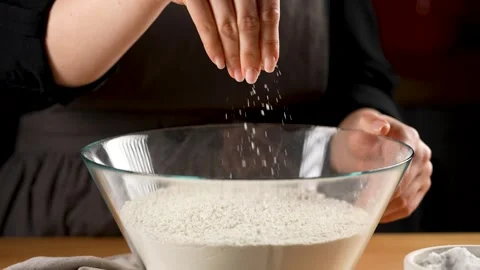 Making Bread - seasoning the flour with coarse salt in slow motion 4k Stock Footage 265888029