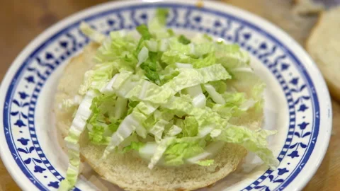 Making a burger at home. Put salad and tomatoes on the bun. Stock Footage 145404680