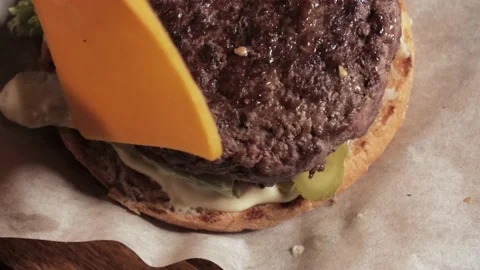 Making a burger, puts a slice of cheese on top of a juicy cutlet. Close-up Stock Footage 136056118