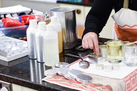 Making candles at home and adding a wick to liquid candle wax Stock Photos