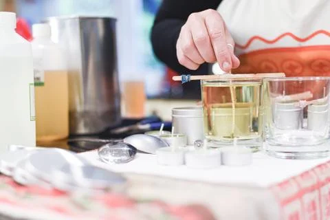 Making candles at home and adding a wick to liquid candle wax Stock Photos