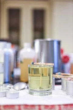 Making candles at home and adding a wick to liquid candle wax Stock Photos