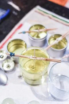 Making candles at home and adding a wick to liquid candle wax Stock Photos