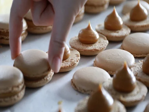 Making Caramel Macaroons : Close up shot of connecting two halves of macaroons Stock Footage 81902077
