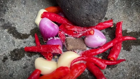 The making of chili paste called sambal , grinding red chili peppers, onion.. Video stock 320360099