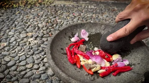 The making of chili paste called sambal , grinding red chili peppers, onion.. Video stock 320360103