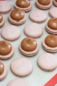 Making chocolate macaroons. Filling shells with chocolate ganache. Selective Stock Photos