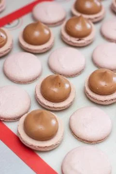 Making chocolate macaroons. Filling shells with chocolate ganache. Selective Stock Photos