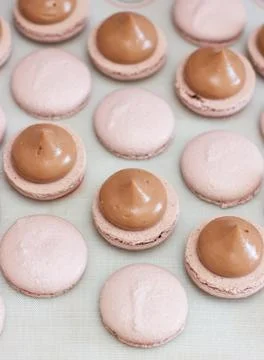 Making chocolate macaroons. Filling shells with chocolate ganache. Selective Stock Photos