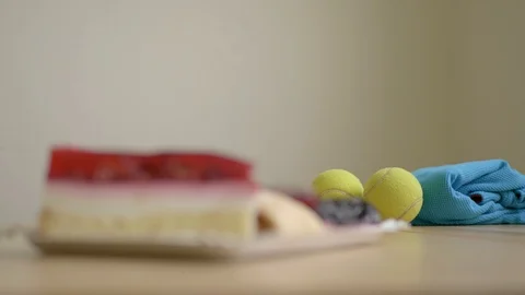 Making choice of sport or sweets, tennis balls and cakes on table Stock Footage 100192698