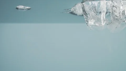 Making cocktail. Slow motion video ice cubes falling into water Stock Footage 125420967